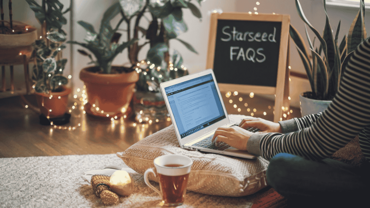Person in a bohemian-style room typing on a laptop, with a chalkboard featuring Starseed FAQs.