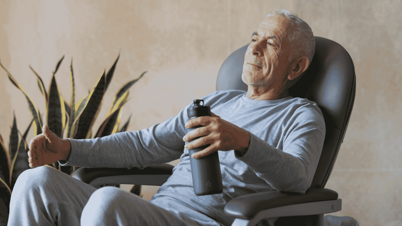 Senior man practicing chair yoga safely with proper support and hydration.